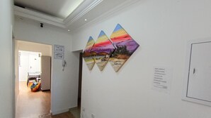 A hallway with a wooden floor, a door at the end, and three artworks on the wall. - WeStay Budget-Unidade 3 (São Paulo)