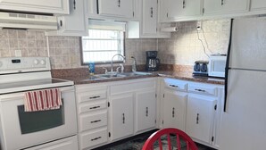 Una cocina moderna con armarios blancos, una silla roja y una mesa de madera.