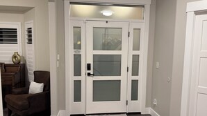 A hallway with a double door, a brown leather chair, a white cushion, and a hexagonal rug. - Utah Vista Chalet: Amazing View Deck, Dual Kitchens & Hot Tub, Games  Sleeps 15 (South Jordan)