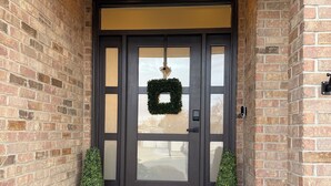 A brick house with a dark front door, two potted plants, and a wreath on the door. - Utah Vista Chalet: Amazing View Deck, Dual Kitchens & Hot Tub, Games  Sleeps 15 (South Jordan)