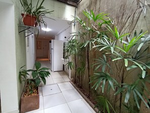 A narrow hallway with tiled flooring, potted plants, and a refrigerator. - WeStay Budget - Unidade 4 (São Paulo)