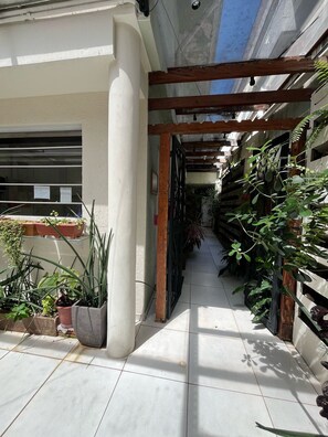 A narrow outdoor corridor with tiled flooring, wooden beams, and potted plants. - WeStay Budget - Unidade 4 (São Paulo)