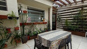 A patio with a table covered by a patterned tablecloth, surrounded by potted plants and a metal fence. - WeStay Budget - Unidade 4 (São Paulo)