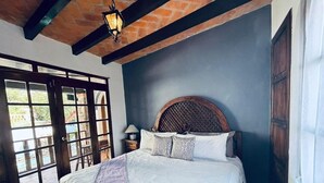 Un dormitorio con una cama grande, un cabecero de madera, una mesita de noche y una ventana con vistas al exterior.