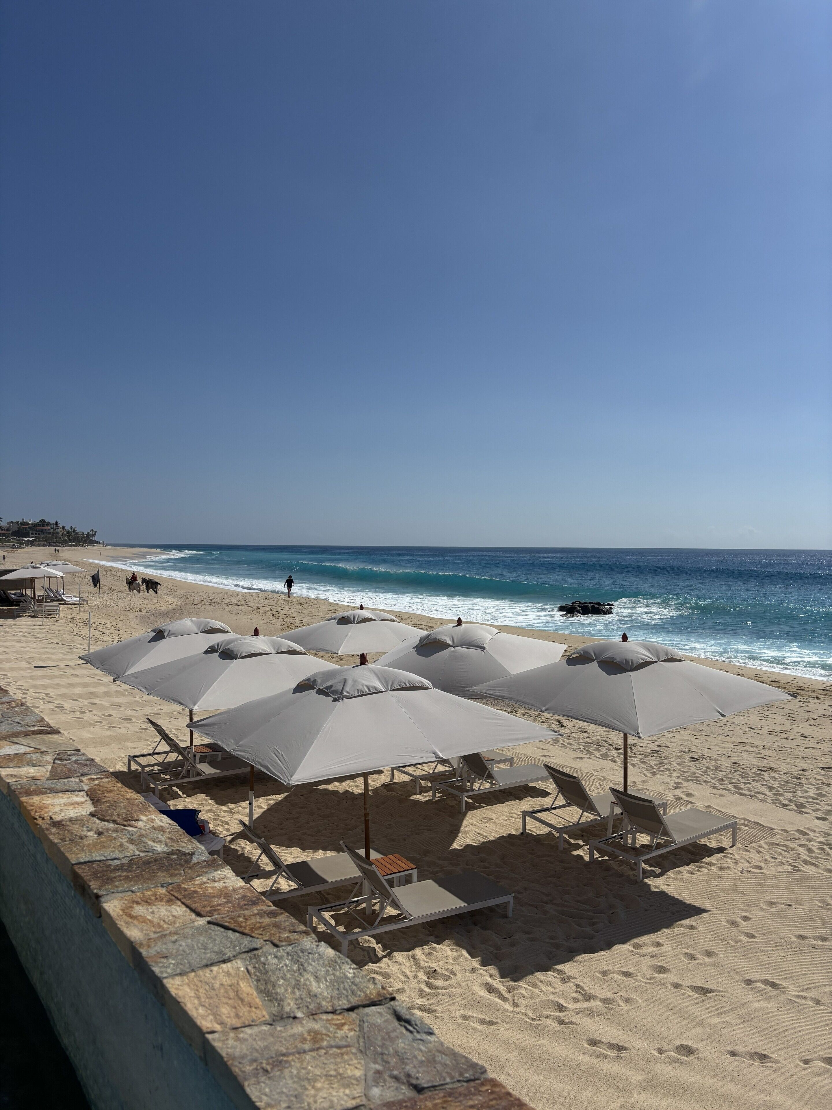Una spiaggia con ombrelloni e lettini, cielo sereno e l'oceano sullo sfondo.