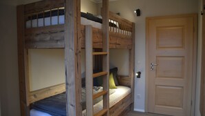 Quarto com beliche, porta de madeira e uma pequena janela.