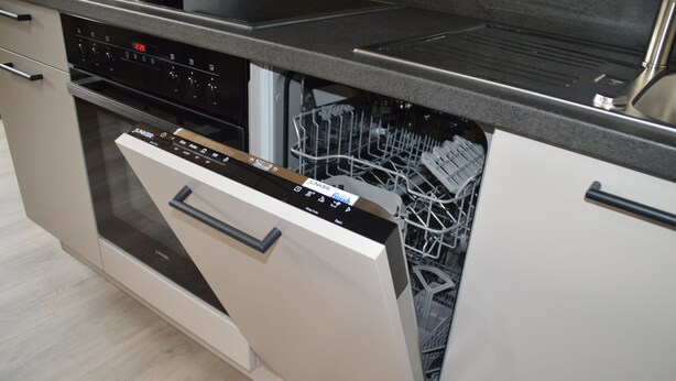 Uma cozinha moderna com máquina de lavar louça, forno e bancada de aço inoxidável.