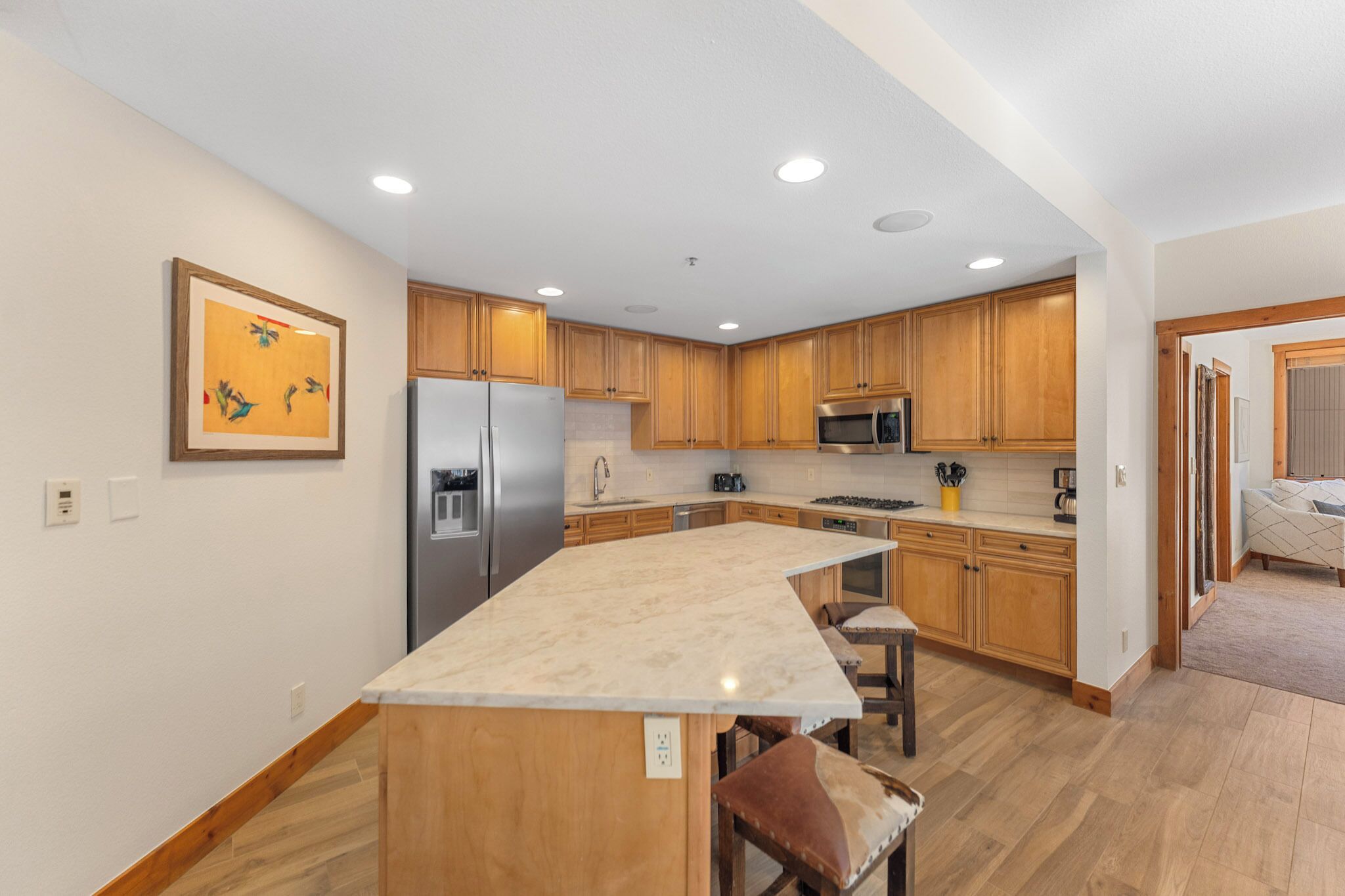 Una cocina moderna con armarios de madera, un refrigerador de acero inoxidable, un microondas y una isla de mármol.