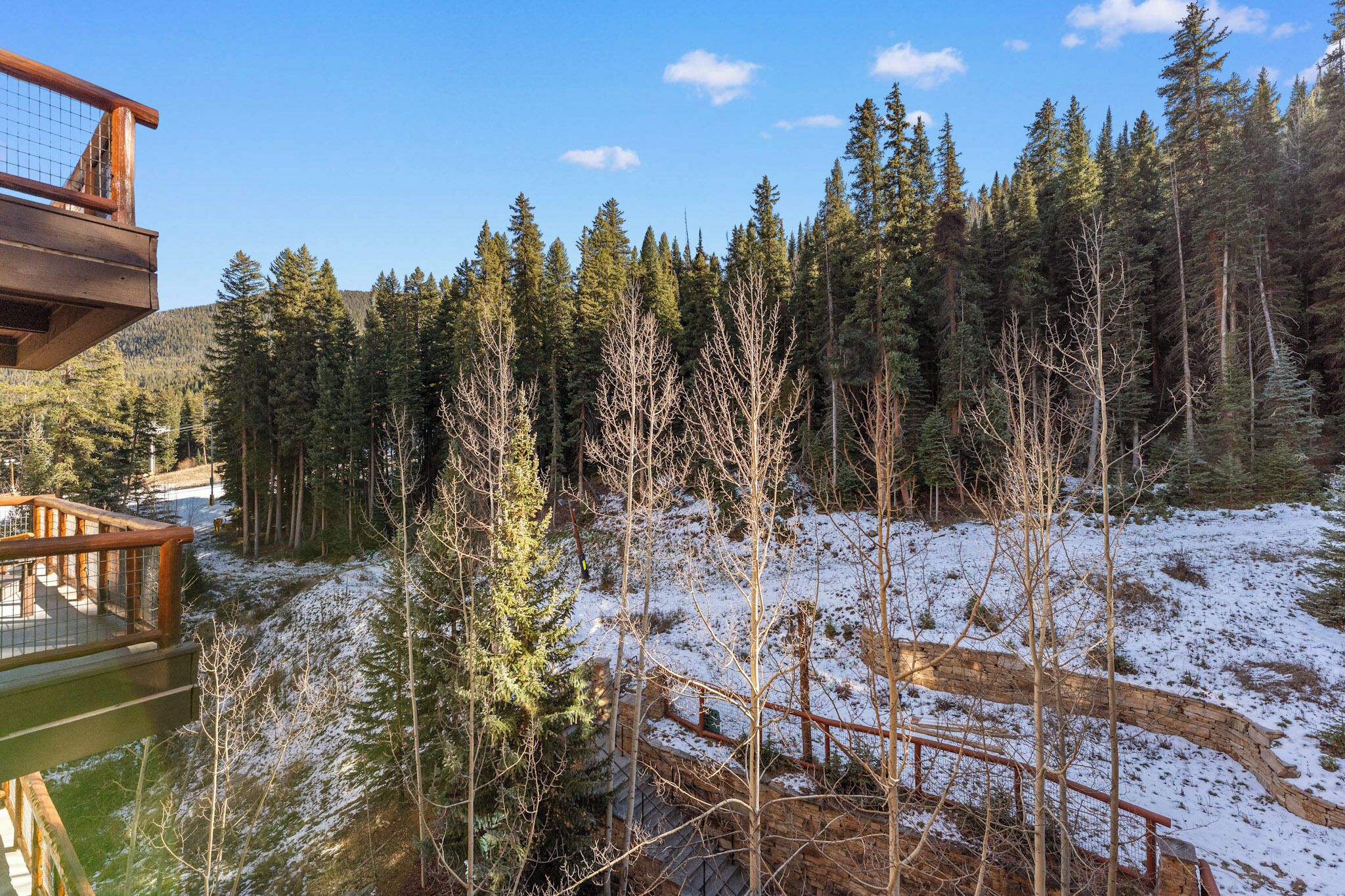 Una terraza de madera con vistas a un bosque nevado y un cielo despejado.