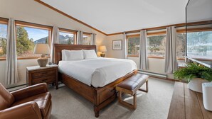 A bedroom with a large bed, wooden headboard, bedside tables with lamps, a bench, and large windows offering mountain views. - Tt1336-3 (Keystone)