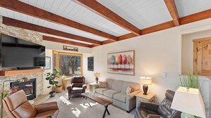 A living room with a fireplace, leather sofas, a flat-screen TV, and a large window. - Tt1336-3 (Keystone)