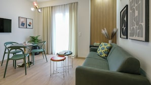 A modern living room with a sofa, dining table, chairs, and a TV. - Pillow by the Sea (Thessaloniki)