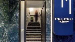 A modern hotel entrance with a marble staircase, a potted plant, and a sign reading 'Pillow by the sea'. - Pillow by the Sea (Thessaloniki)