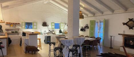 Un intérieur spacieux et bien éclairé, avec de hauts plafonds, un coin repas central et une cheminée.