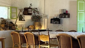 A dining area with wicker chairs, a table, and a hanging light fixture. - Cortijo Huerta Galindo (Alanís)