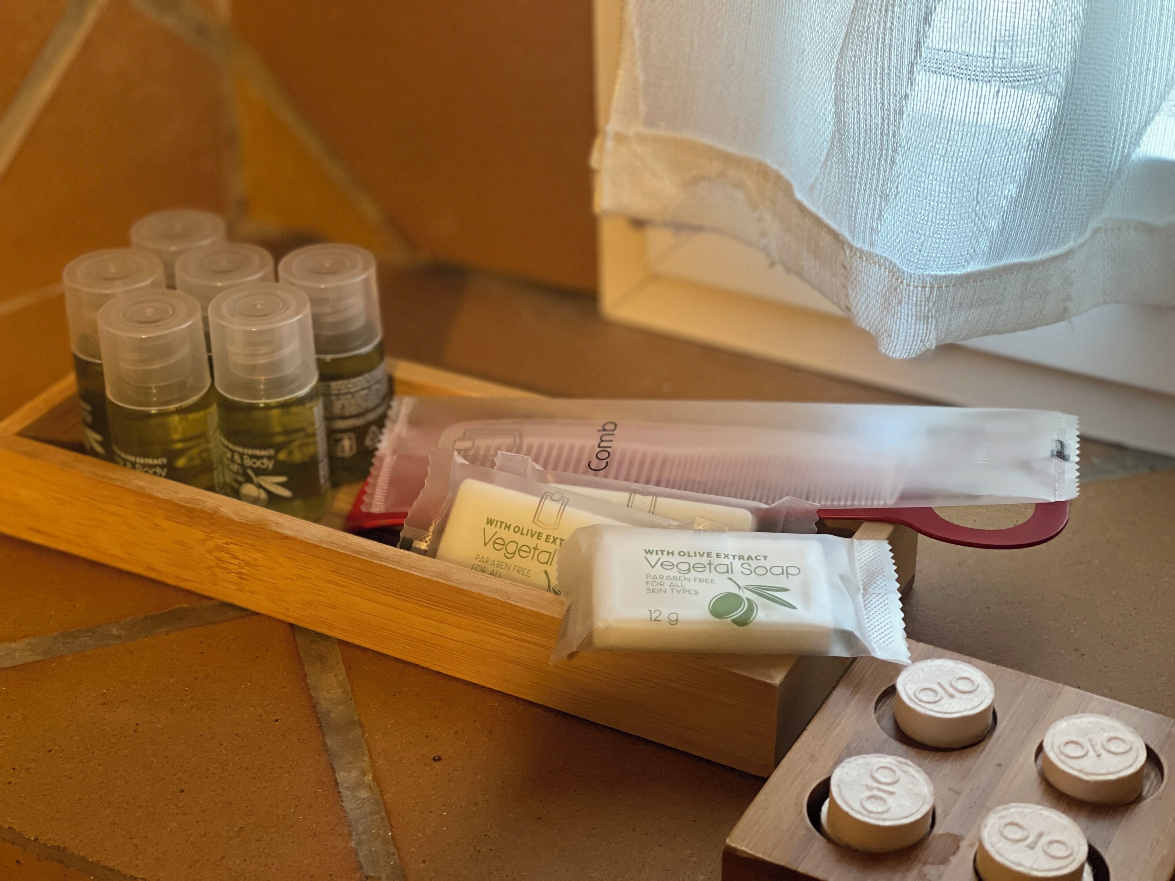 A wooden tray with various toiletries including bottles of body wash, a comb, and a bar of soap.