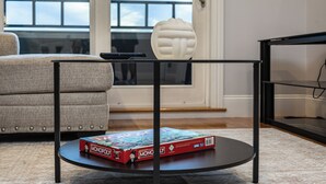 Ein Wohnzimmer mit einer Couch, einem Couchtisch mit einem Gesellschaftsspiel und einem dekorativen Gegenstand.