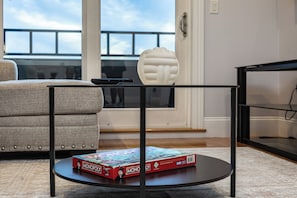 A living room with a sofa, a coffee table with a board game, and a decorative item.