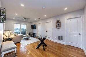 A modern living room with a glass-top table, a sofa, a coffee table, and a ceiling fan.