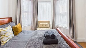 A hotel room with a bed, a window, and curtains.