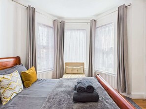 Quarto de hotel com cama, janela e cortinas.