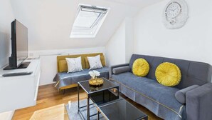 A modern living room with a sofa, a coffee table, a TV, and a skylight.
