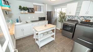 Una cocina moderna con armarios blancos, un refrigerador de acero inoxidable, un microondas y un horno empotrado.