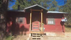 A small log cabin with a porch, two windows, and a satellite dish. - Cabin 2 @ Lazy Day Cabins (Mayhill)