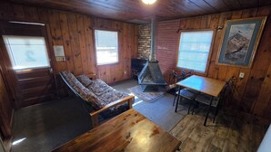 A cozy cabin interior with a sofa, a wooden table, a fireplace, and a painting on the wall. - Cabin 2 @ Lazy Day Cabins (Mayhill)