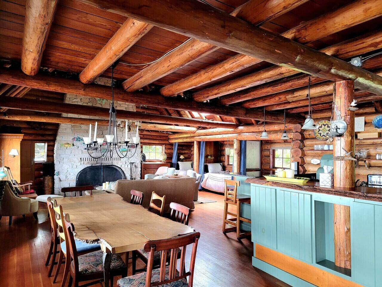 L’intérieur d’un chalet rustique comprend une table à manger en bois, des canapés, une cheminée et un coin cuisine.