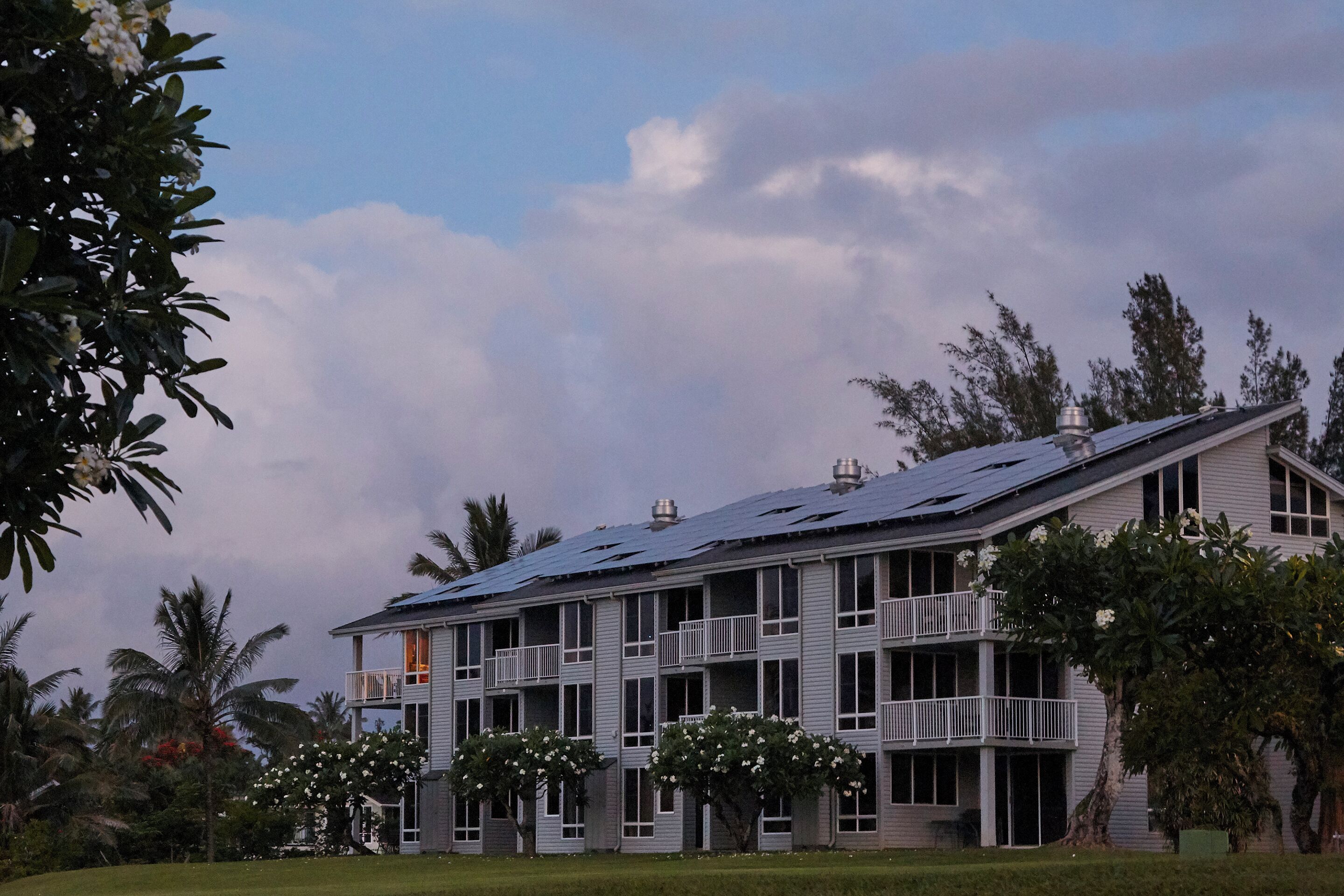 Un edificio de varios pisos con balcones y paneles solares en el techo.