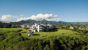 A resort with multiple-story buildings, a golf course, and a mountainous backdrop.