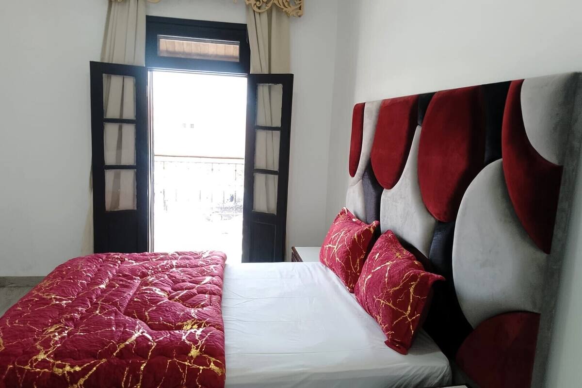 A bedroom with a bed, a window with curtains, and a view outside.