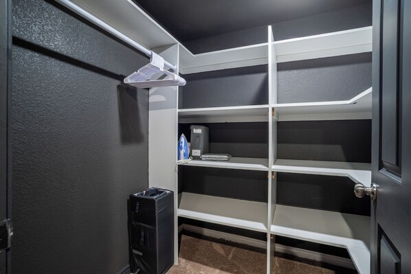 A closet with white shelves, a hanging rod, and a small heater.