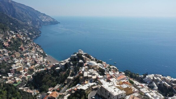 Una cittadina costiera con una chiesa imponente su una collina, una spiaggia e vista sul mare.