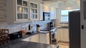 A modern kitchen with white cabinetry, a black marble countertop, and a built-in oven. - Oceanfront Condo at Bonita Beach Club – Pool, Tennis, Private Beach Access! (Bonita Springs)