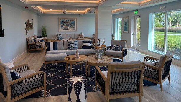 A spacious lounge area with a sofa set, wooden chairs, a coffee table, and a decorative rug. - Oceanfront Condo at Bonita Beach Club – Pool, Tennis, Private Beach Access! (Bonita Springs)