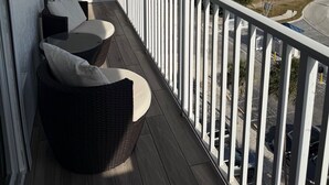A balcony with wicker furniture and a view of a marina and buildings. - Oceanfront Condo at Bonita Beach Club – Pool, Tennis, Private Beach Access! (Bonita Springs)