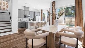 Una cocina moderna con armarios grises, una isla central y un área de comedor con mesa de madera y sillas acolchadas.