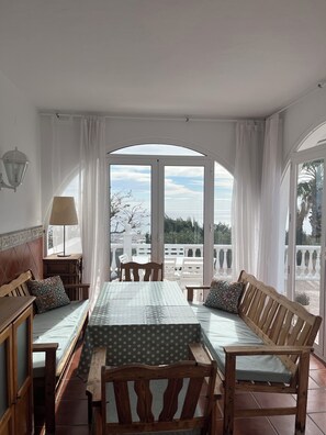 Ein Zimmer mit einem Bett, einer hölzernen Bank, einem Tisch und Blick auf einen Balkon mit Gartenmöbeln.