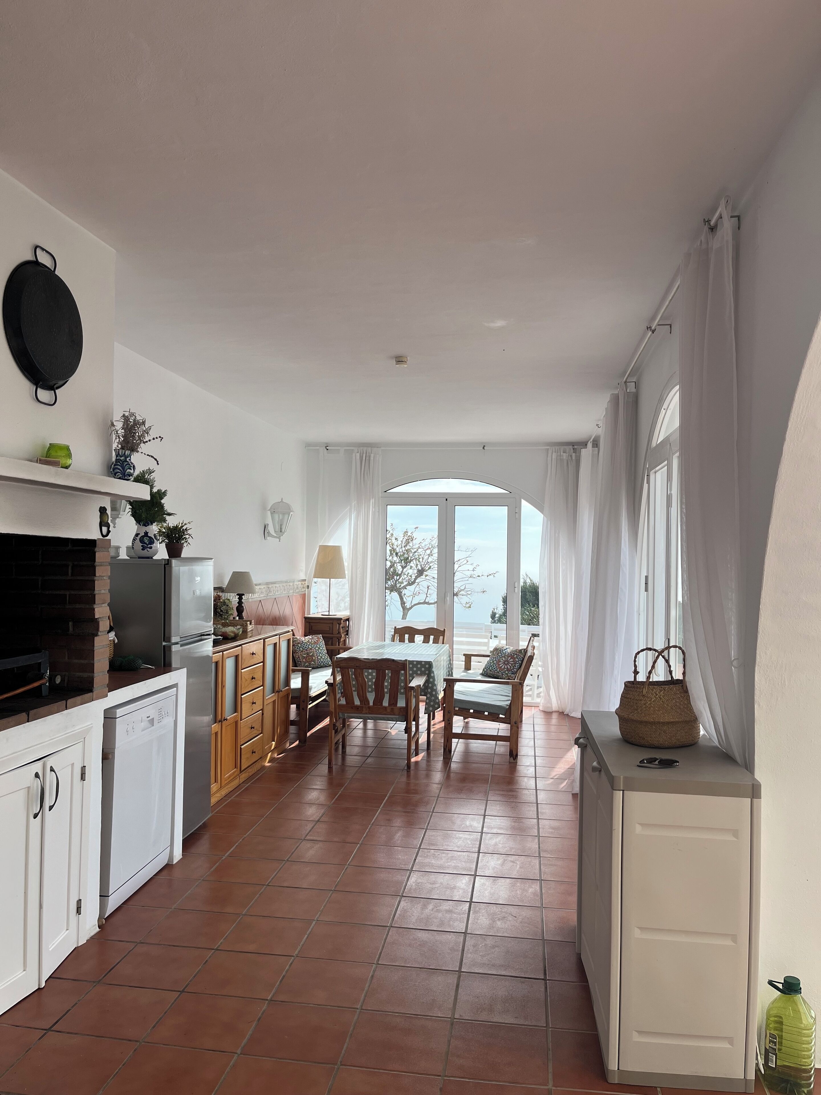 A kitchen with a dining area, a view to the outside, and a window with curtains.