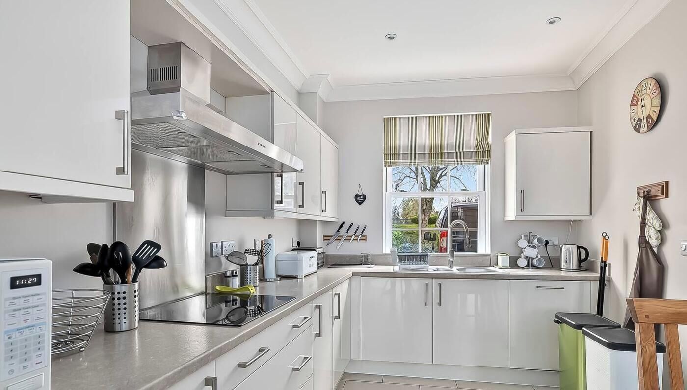 A modern kitchen with white cabinets, stainless steel appliances, and a window with a view.