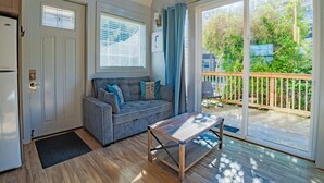 Ein gemütliches Wohnzimmer mit grauem Sofa, einem Holztisch und einer Glastür zum Balkon.