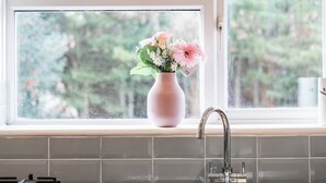 A kitchen with a window, a pink vase with flowers, and a faucet. - Charming Thames Ditton Apt- Sleeps 6- Free Parking (Thames Ditton)