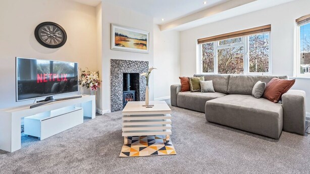 A modern living room with a flat-screen TV, a fireplace, a sofa, and a large window. - Charming Thames Ditton Apt- Sleeps 6- Free Parking (Thames Ditton)