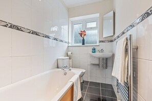 A bathroom with a bathtub, toilet, sink, and window. - Charming Thames Ditton Apt- Sleeps 6- Free Parking (Thames Ditton)