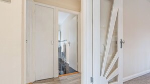 A hallway with a wooden floor, a white door, and a glass door leading to a staircase. - Charming Thames Ditton Apt- Sleeps 6- Free Parking (Thames Ditton)