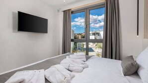 A hotel room with a bed, a flat-screen TV mounted on the wall, and a large window with curtains. - HADRIE Luxury Resort and Villas Krk (Krk)