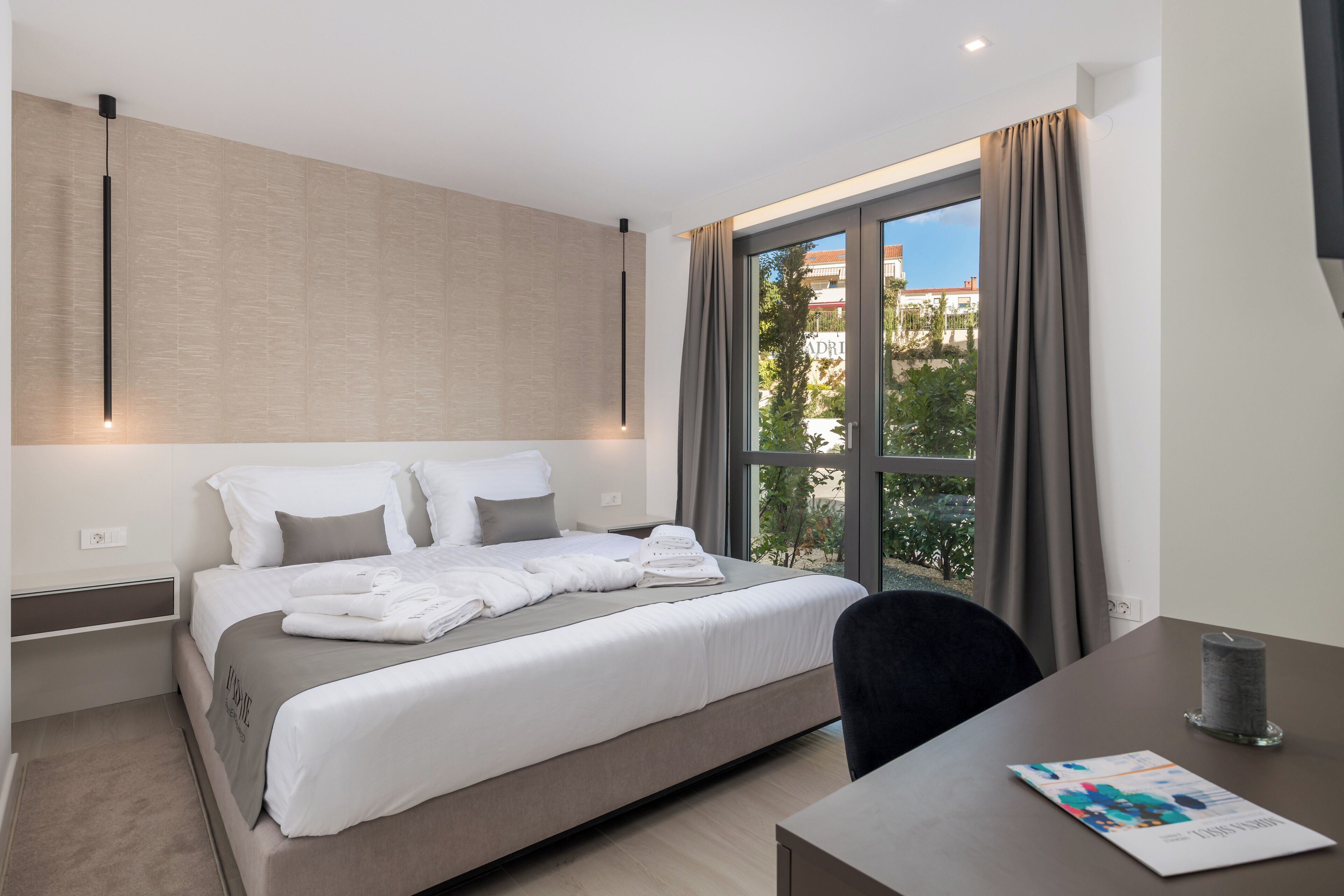 Una habitación de hotel moderna con una cama grande, un escritorio y una ventana con cortinas.