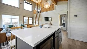 Una cocina amplia con una isla grande, techo de madera e iluminación colgante.